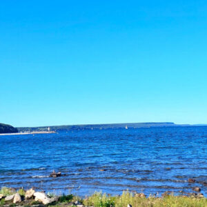 photo of deep blue coloured water from wiarton beach with sailing vessels in port in distance