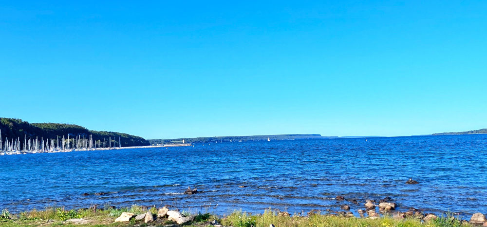 Wiarton-Beach-August photo of deep blue coloured water from wiarton beach with sailing vessels in port in distance